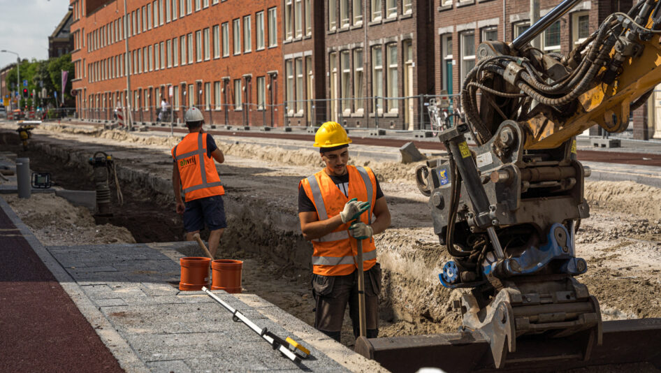 Grondwerkers assisteren kraanmachinist