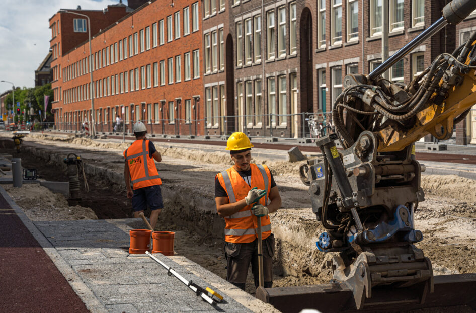 Grondwerkers assisteren kraanmachinist